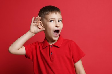 Photo of Little boy showing hand to ear gesture on red background