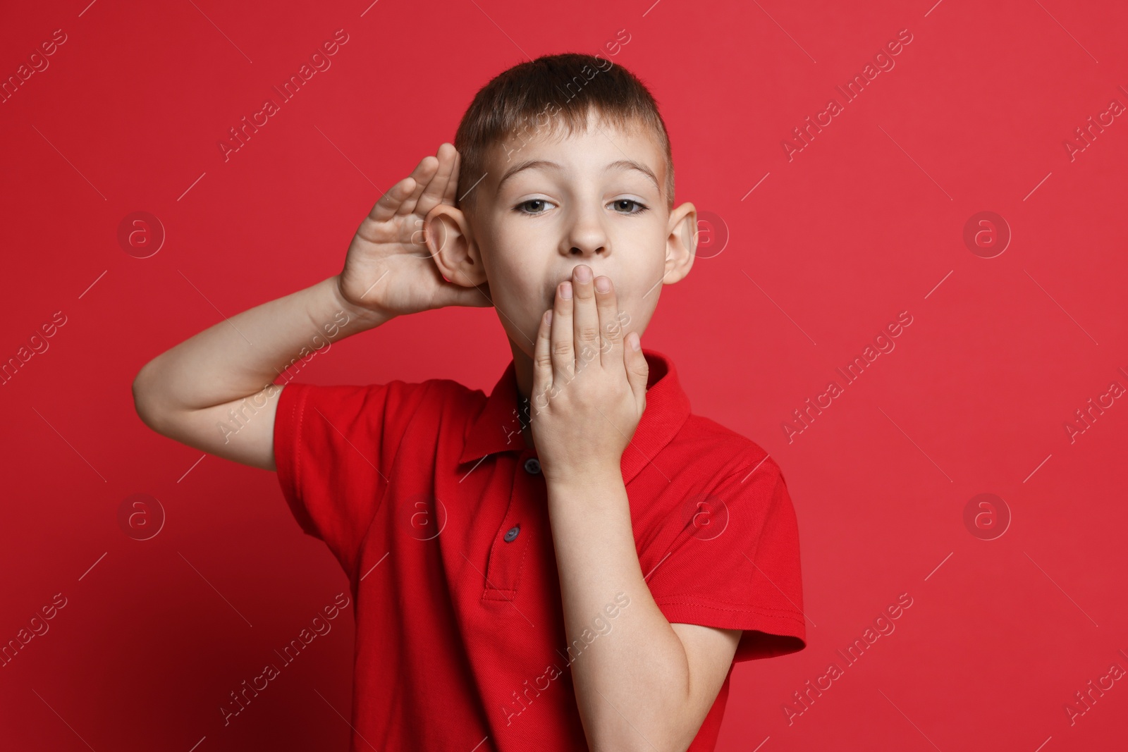 Photo of Little boy showing hand to ear gesture on red background