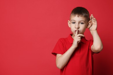 Little boy showing hand to ear gesture on red background, space for text