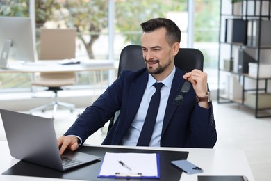 Photo of Happy banker working with laptop at table in office