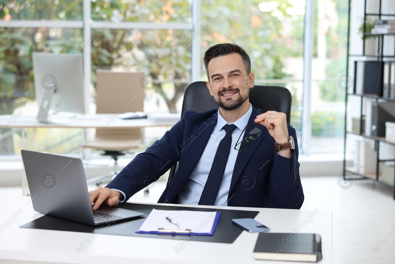 Photo of Portrait of smiling banker at table in office