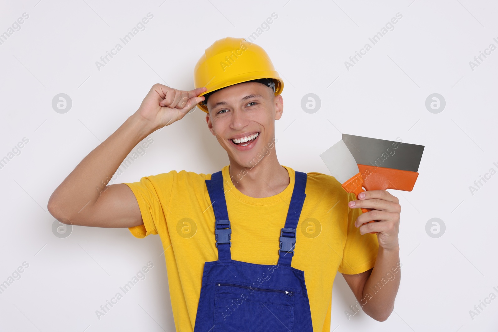 Photo of Portrait of young decorator with putty knives on white background