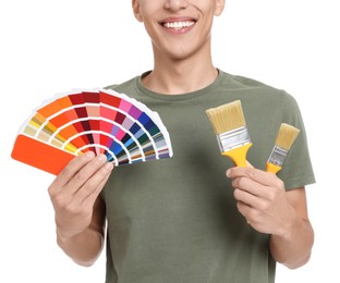 Photo of Young decorator with color palettes and brushes on white background, closeup