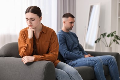 Photo of Offended couple ignoring each other at home, selective focus