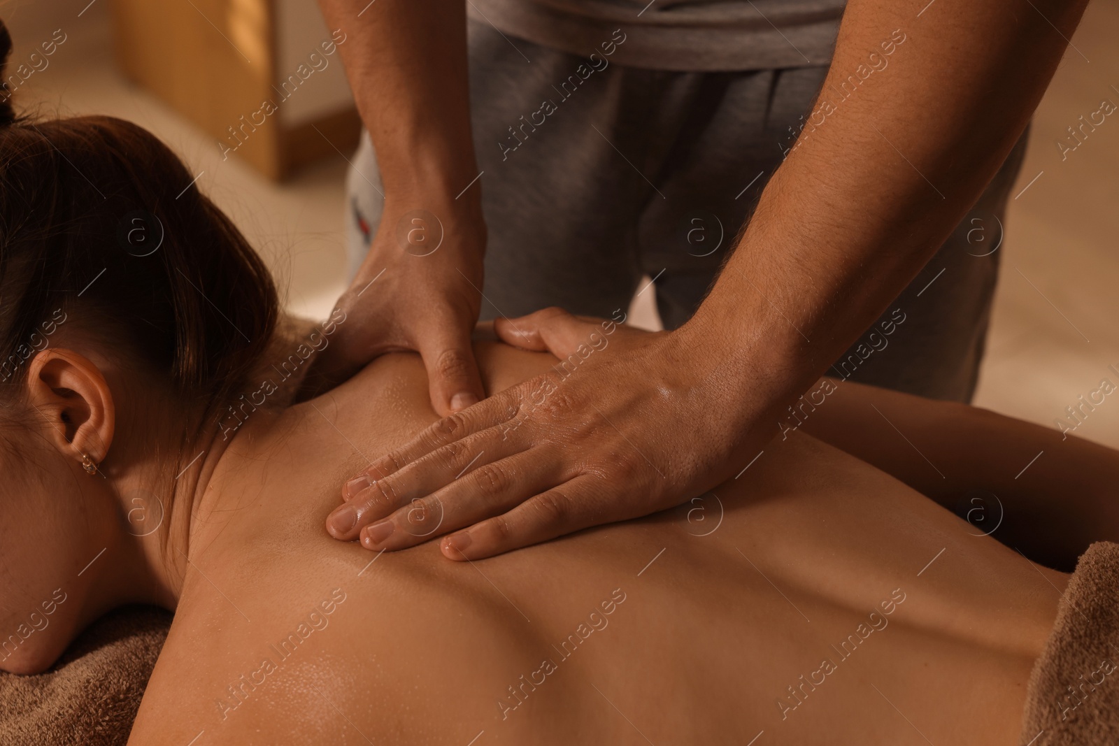 Photo of Osteopath massaging woman's back on couch indoors, closeup. Manual therapy