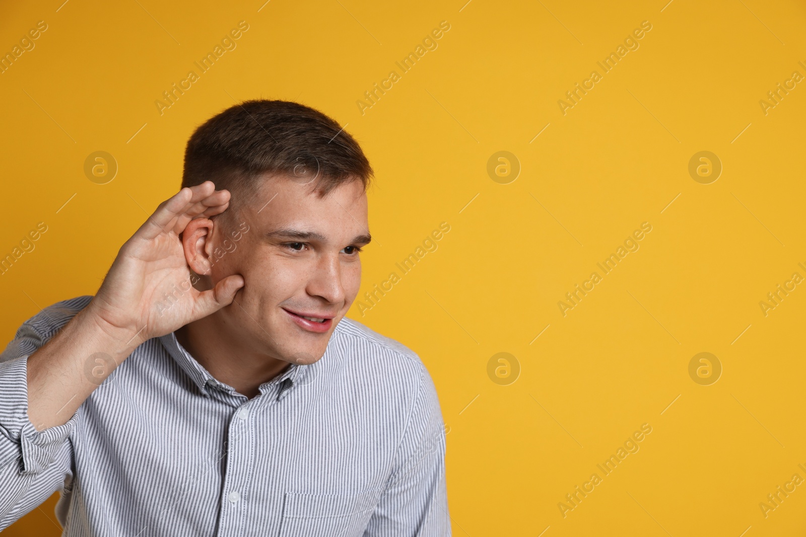 Photo of Man showing hand to ear gesture on orange background, space for text