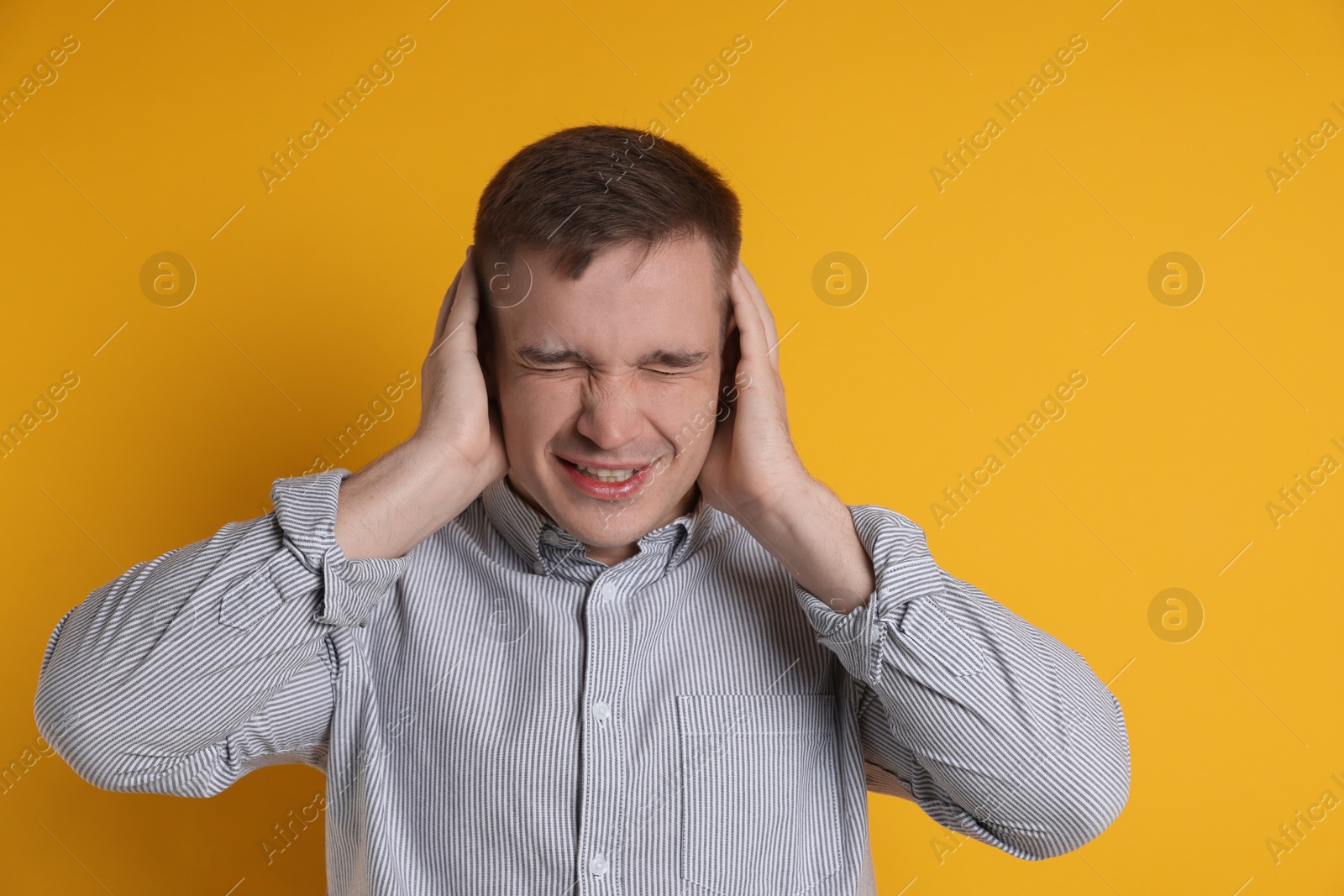 Photo of Man covering his ears on orange background