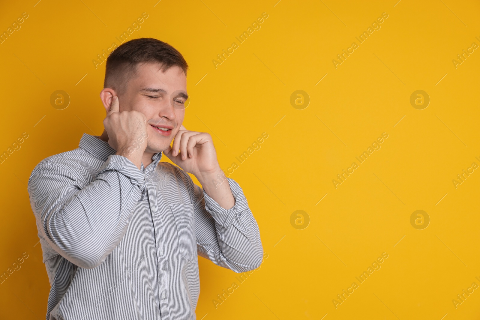 Photo of Man covering his ears with fingers on orange background, space for text