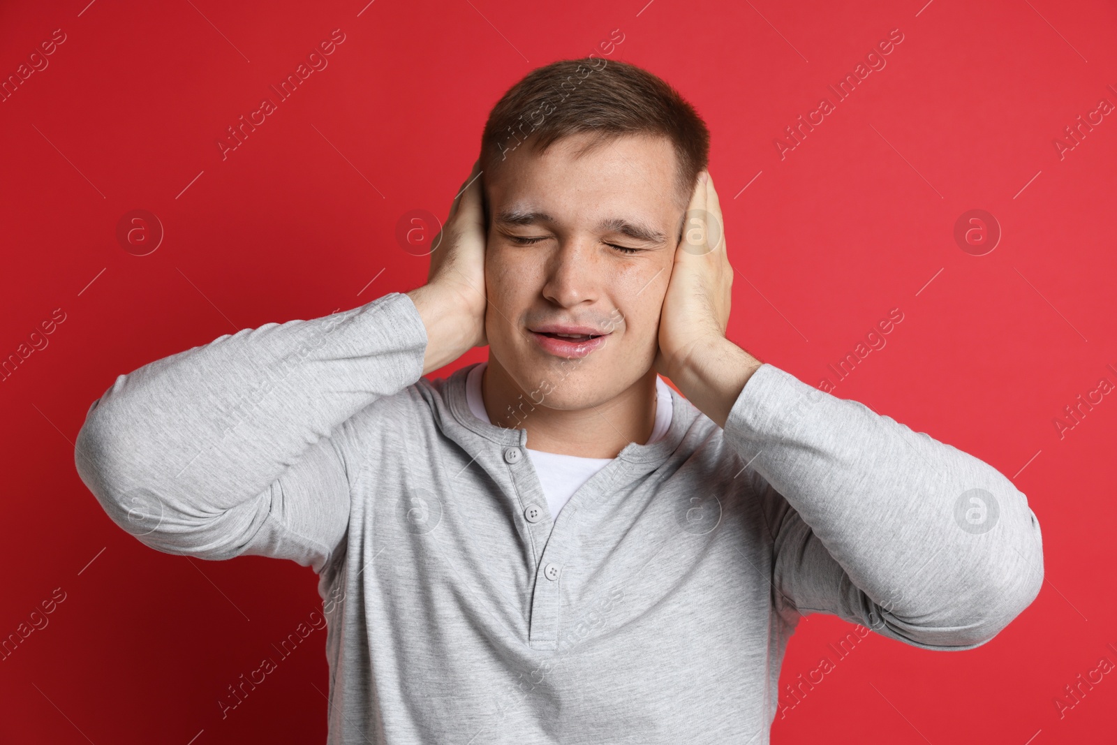 Photo of Man covering his ears on red background