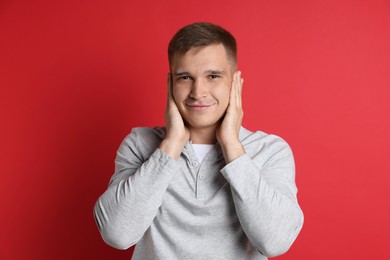 Photo of Man covering his ears on red background