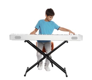 Cute boy playing synthesizer on white background