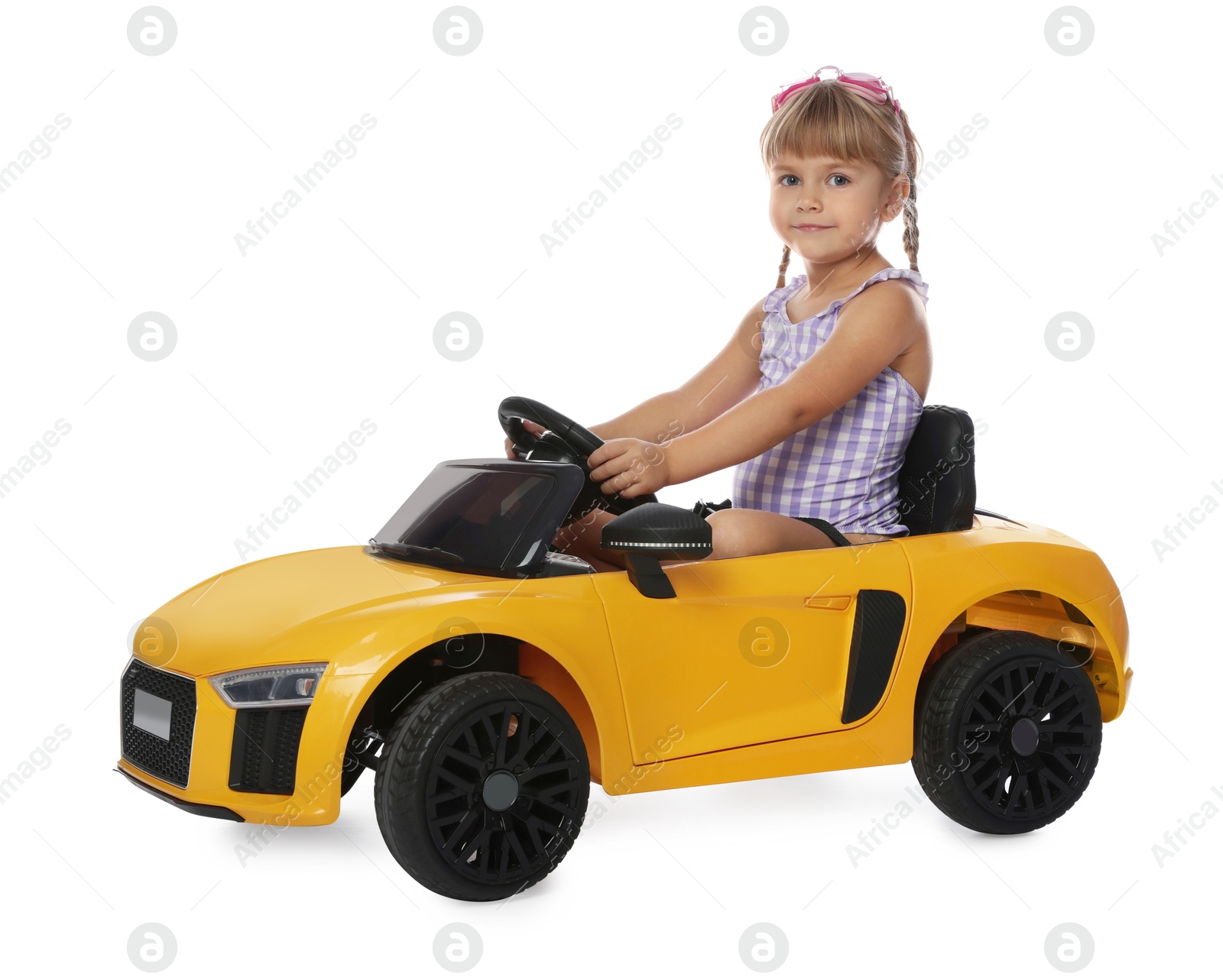 Photo of Cute little girl wearing swimsuit in toy car on white background