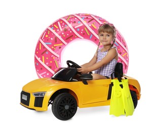 Photo of Cute little girl in swimsuit with inflatable ring, flippers and toy car on white background