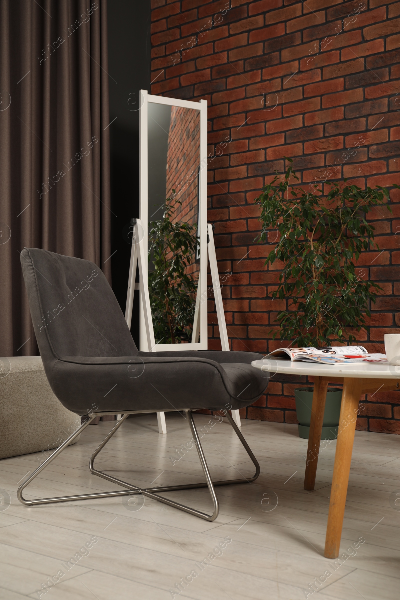 Photo of Soft armchair, coffee table, mirror and houseplant in cozy living room. Interior design