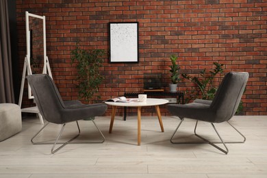 Soft armchairs, coffee table, mirror and houseplants in cozy living room. Interior design