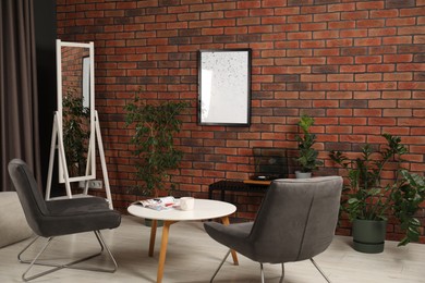 Photo of Soft armchairs, coffee table, mirror and houseplants in cozy living room. Interior design