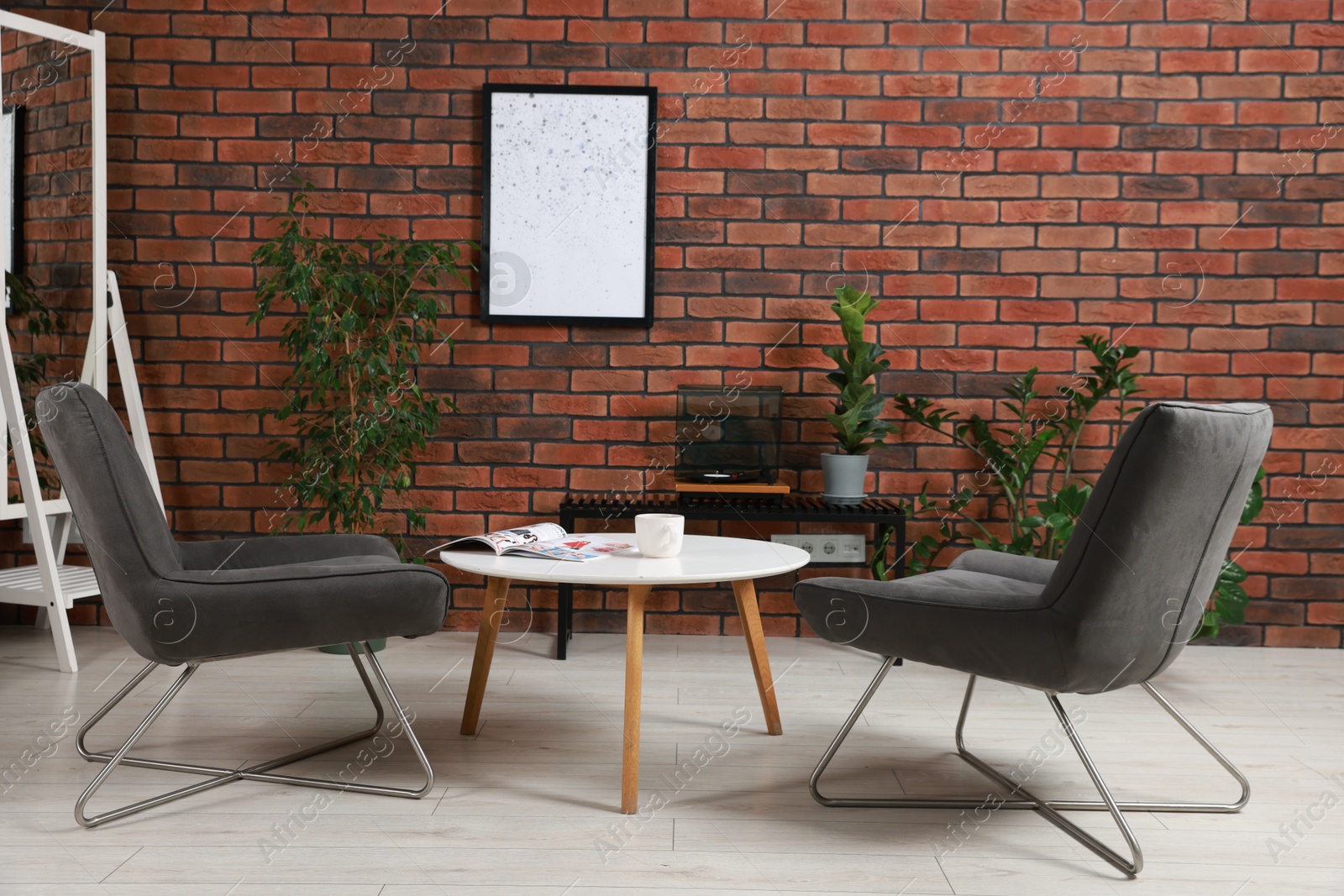 Photo of Soft armchairs, coffee table, mirror and houseplants in cozy living room. Interior design