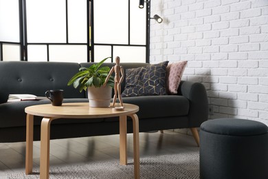 Photo of Coffee table, soft sofa and pouf in stylish living room. Interior design