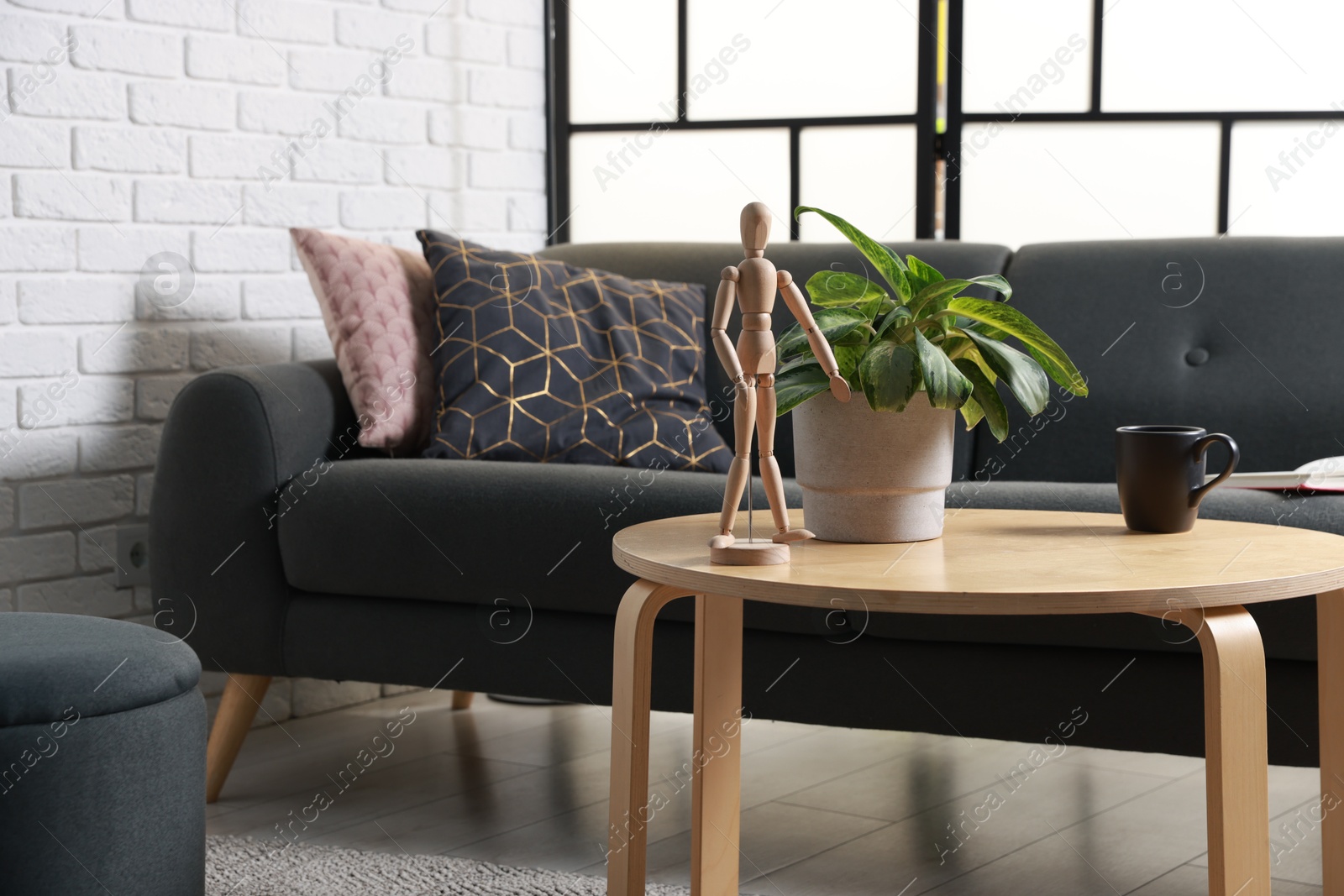 Photo of Coffee table, soft sofa and pouf in stylish living room. Interior design