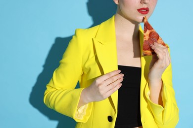 Photo of Stylish woman with piece of pizza on light blue background, closeup. Space for text