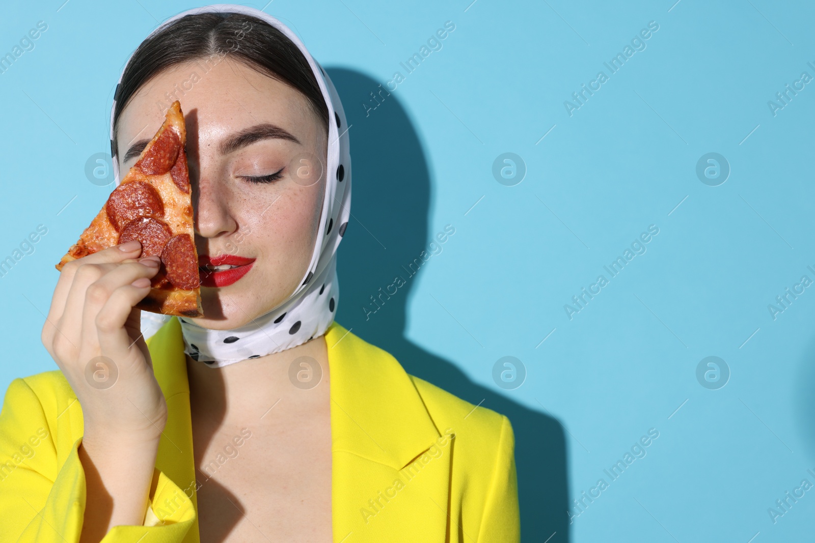 Photo of Stylish woman with piece of pizza on light blue background, space for text