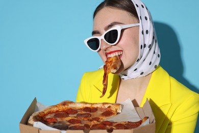 Photo of Stylish woman with delicious pizza on light blue background