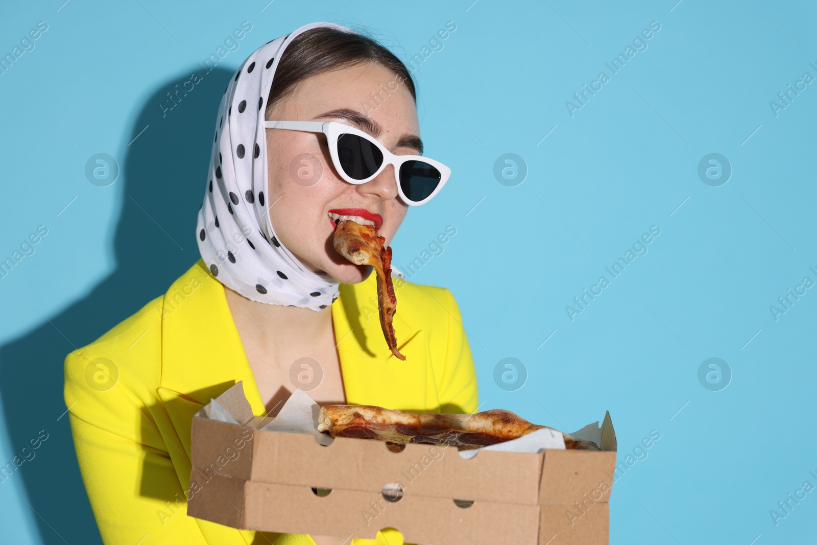 Photo of Stylish woman with delicious pizza on light blue background, space for text