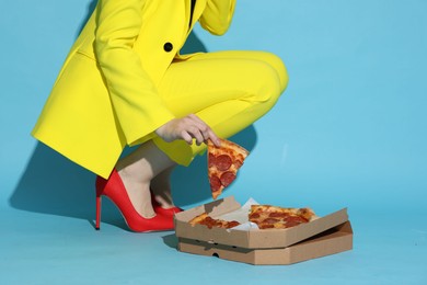 Stylish woman with delicious pizza on light blue background, closeup