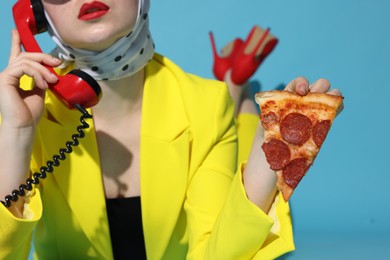 Photo of Woman with delicious pizza and telephone on light blue background, closeup