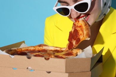 Photo of Woman in sunglasses with delicious pizza on light blue background, closeup