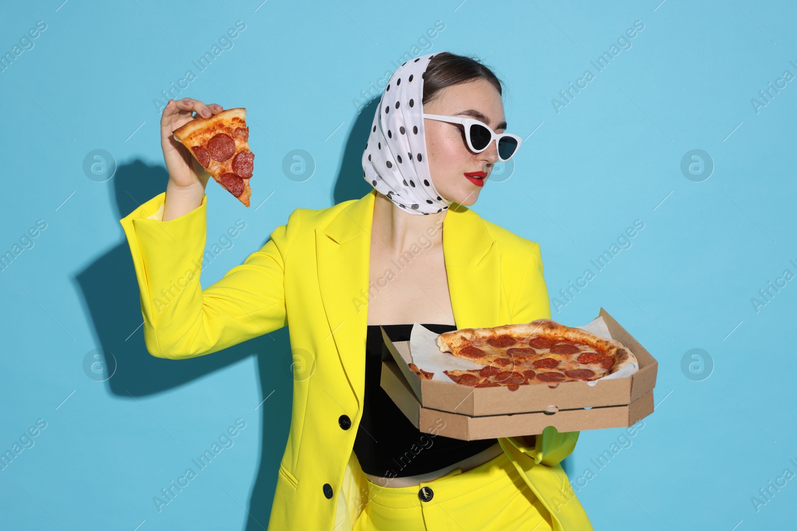 Photo of Stylish woman with delicious pizza on light blue background