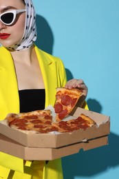 Photo of Stylish woman with delicious pizza on light blue background