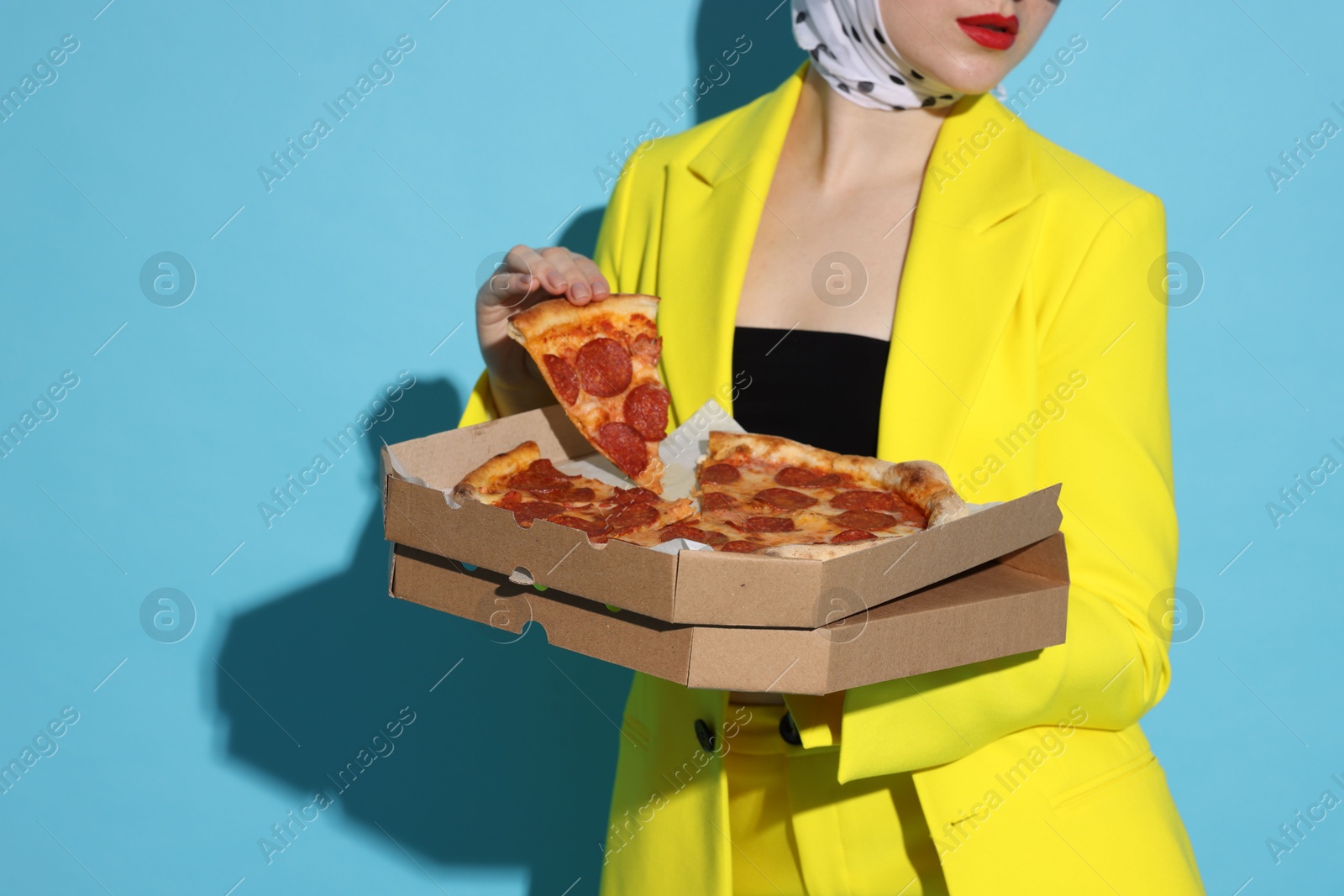 Photo of Stylish woman with delicious pizza on light blue background, closeup