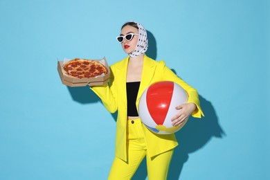 Photo of Stylish woman with delicious pizza and inflatable ball on light blue background