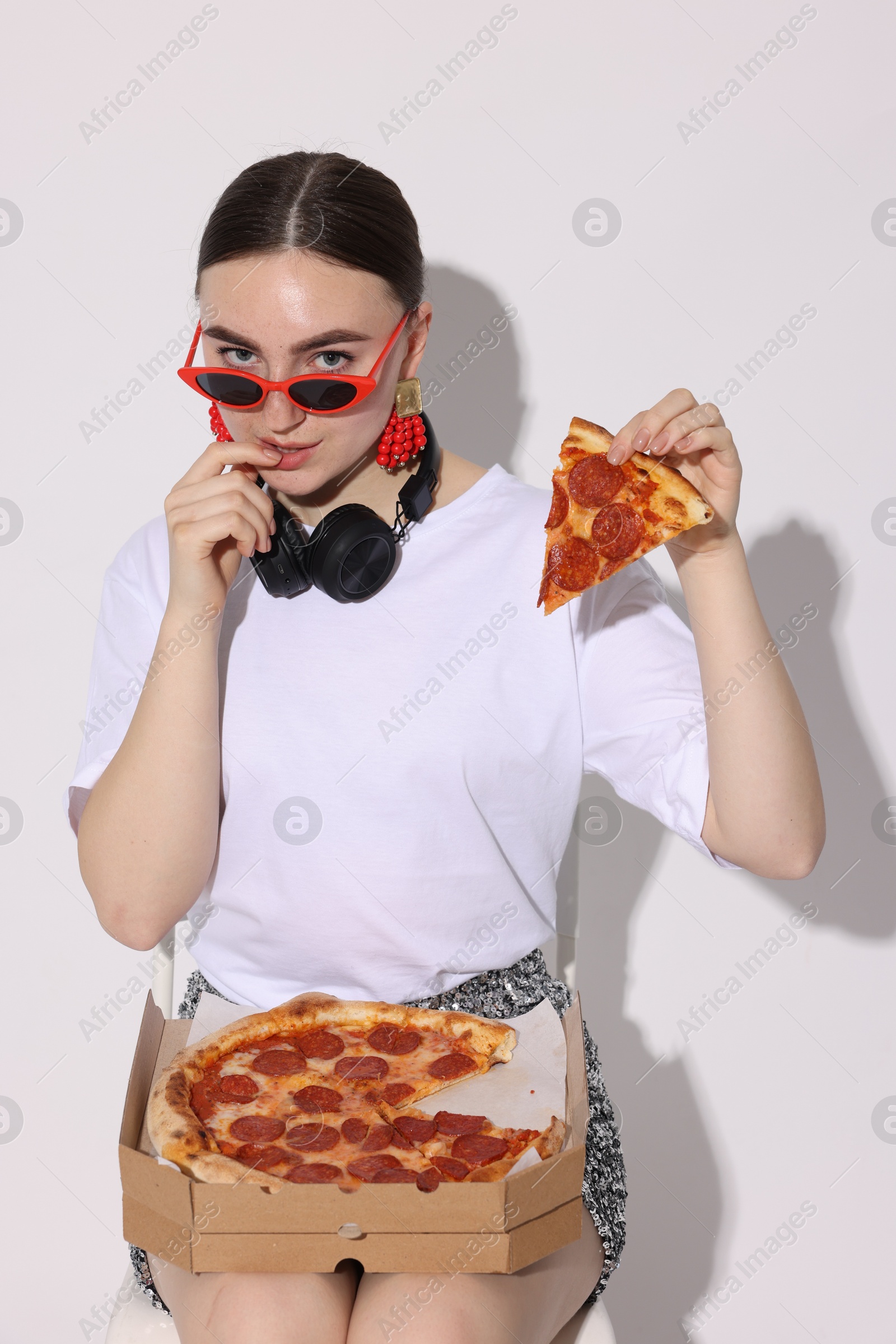 Photo of Woman in sunglasses with piece of pizza on white background