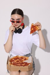 Photo of Woman in sunglasses with piece of pizza on white background