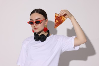 Photo of Woman in sunglasses with piece of pizza on white background