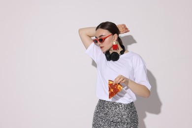 Photo of Woman in sunglasses with piece of pizza on white background, space for text