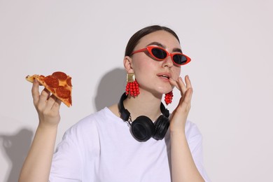 Woman in sunglasses with piece of pizza on white background