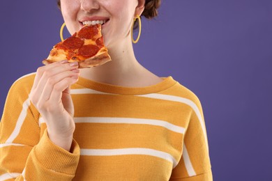 Photo of Woman eating pizza on violet background, closeup