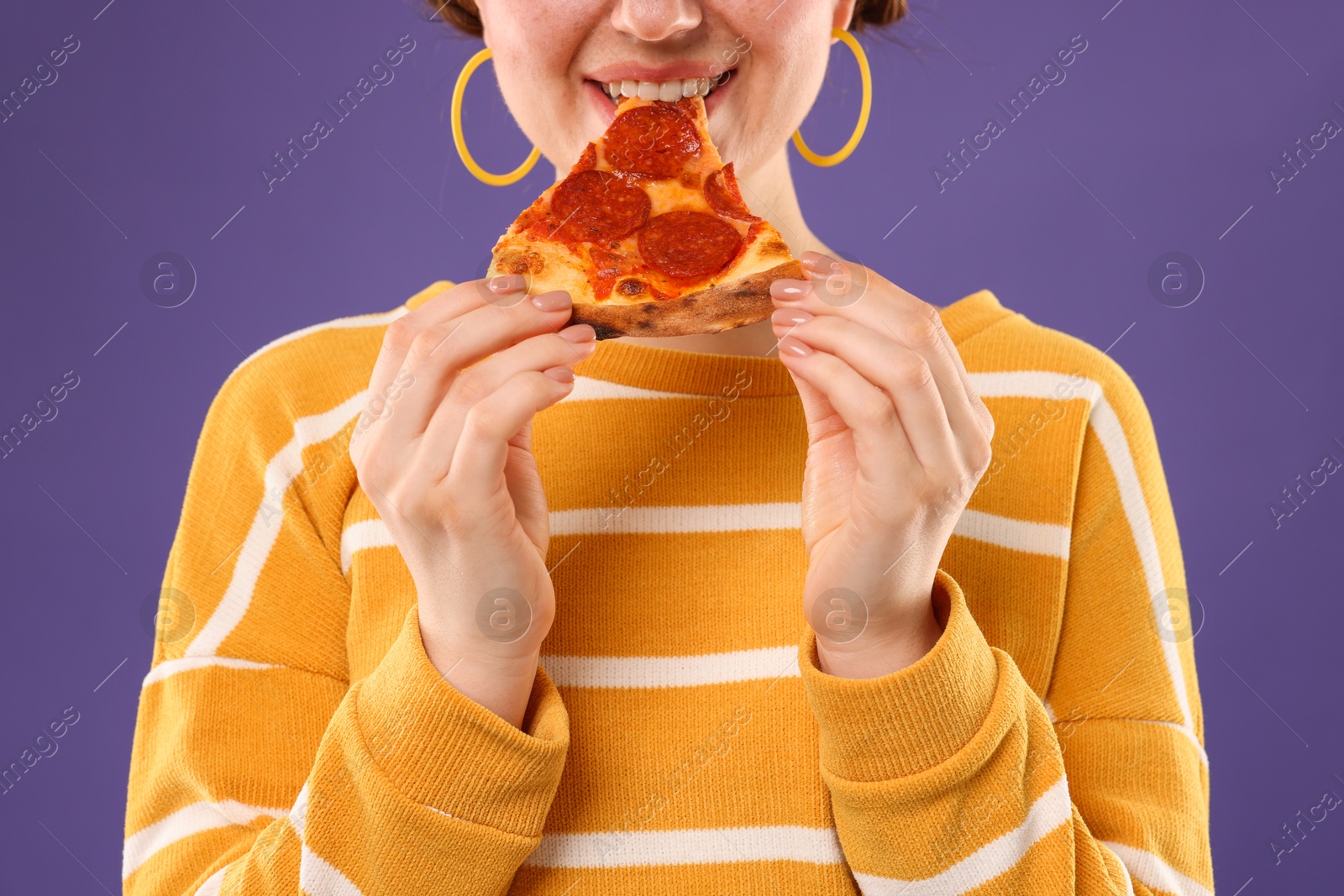 Photo of Woman eating pizza on violet background, closeup