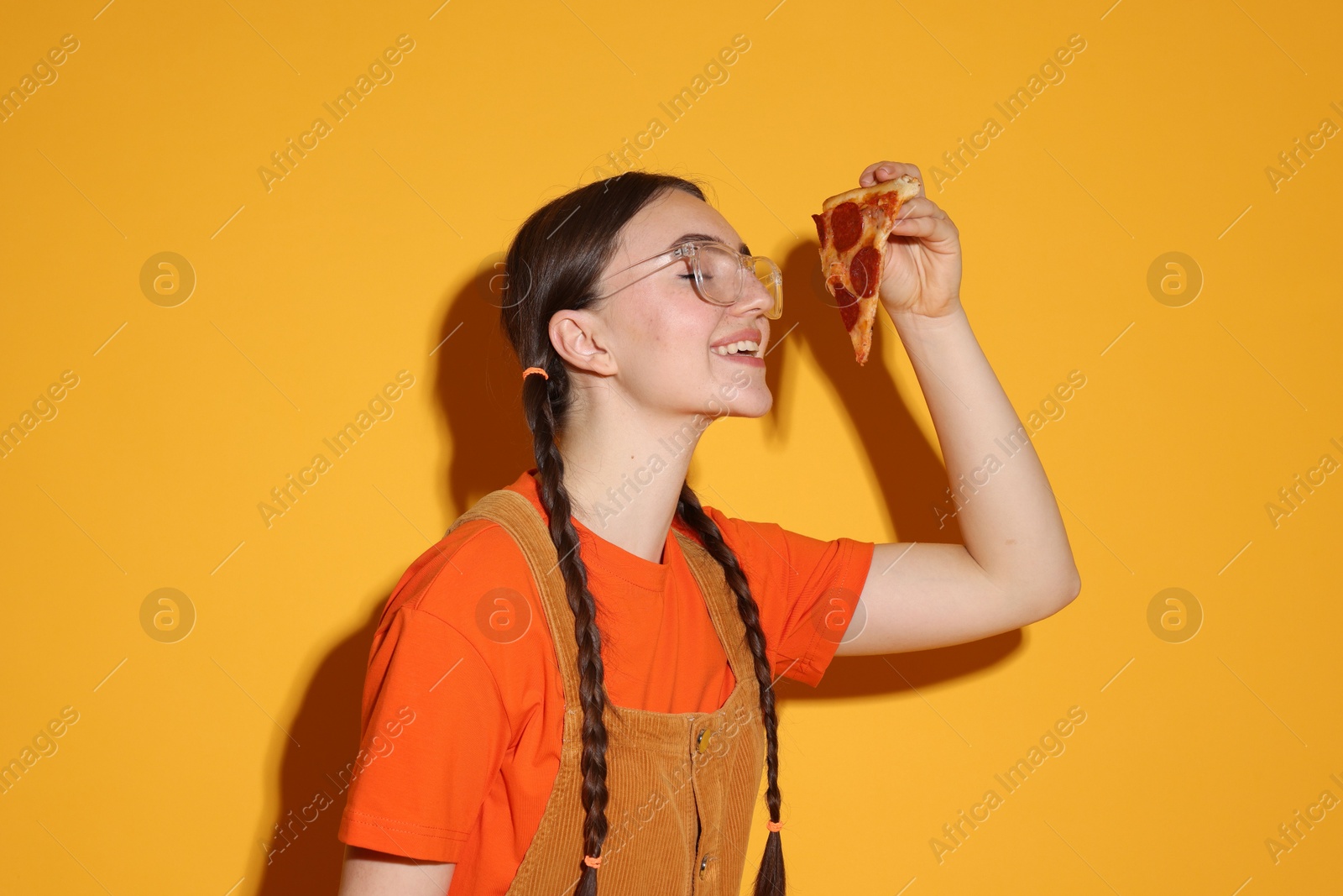 Photo of Beautiful woman with piece of delicious pizza on orange background