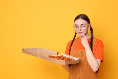 Photo of Beautiful woman with delicious pizza on orange background, space for text