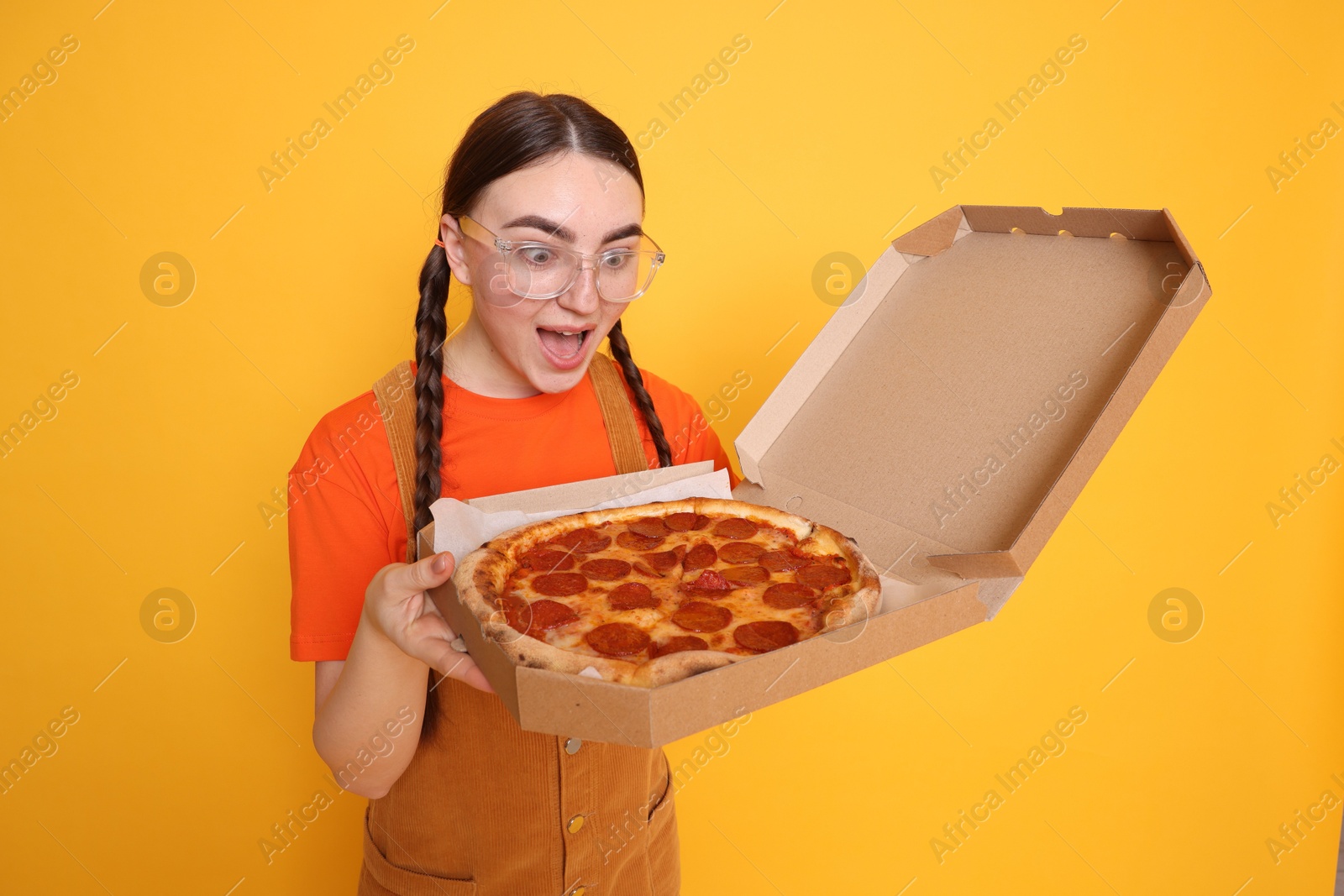 Photo of Surprised woman with delicious pizza on orange background