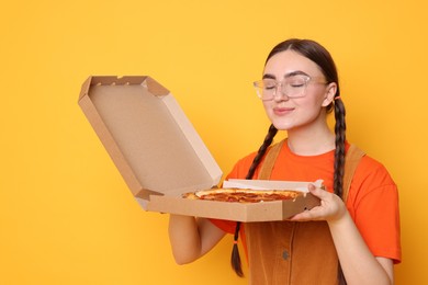 Photo of Beautiful woman with delicious pizza on orange background