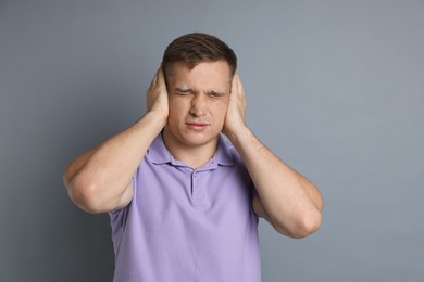 Photo of Man covering his ears on gray background