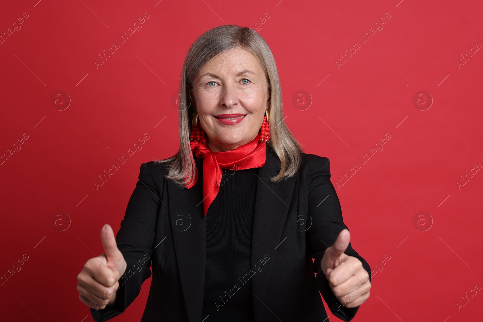 Photo of Senior woman showing thumbs up on red background