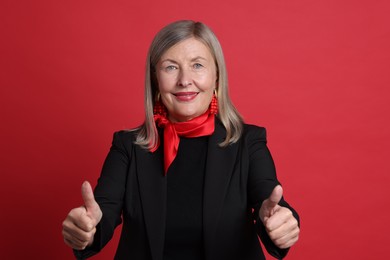 Photo of Senior woman showing thumbs up on red background