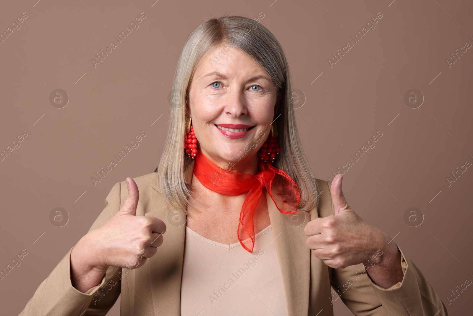 Photo of Senior woman showing thumbs up on brown background