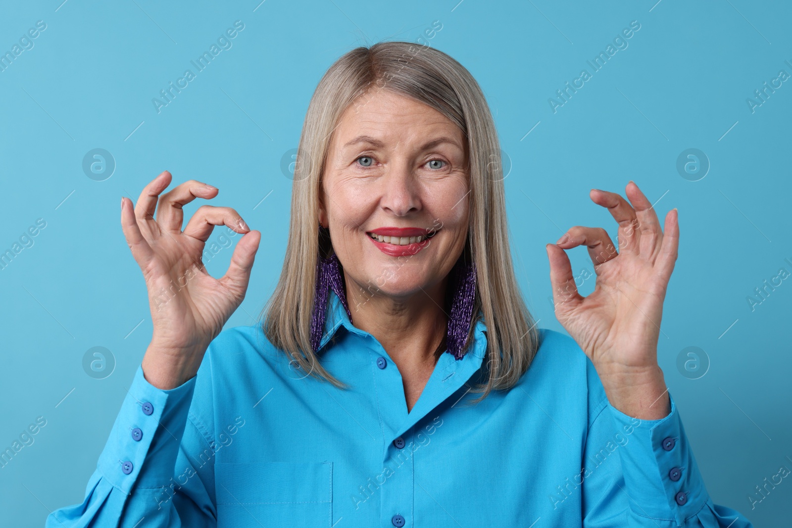 Photo of Senior woman showing okay gesture on blue background